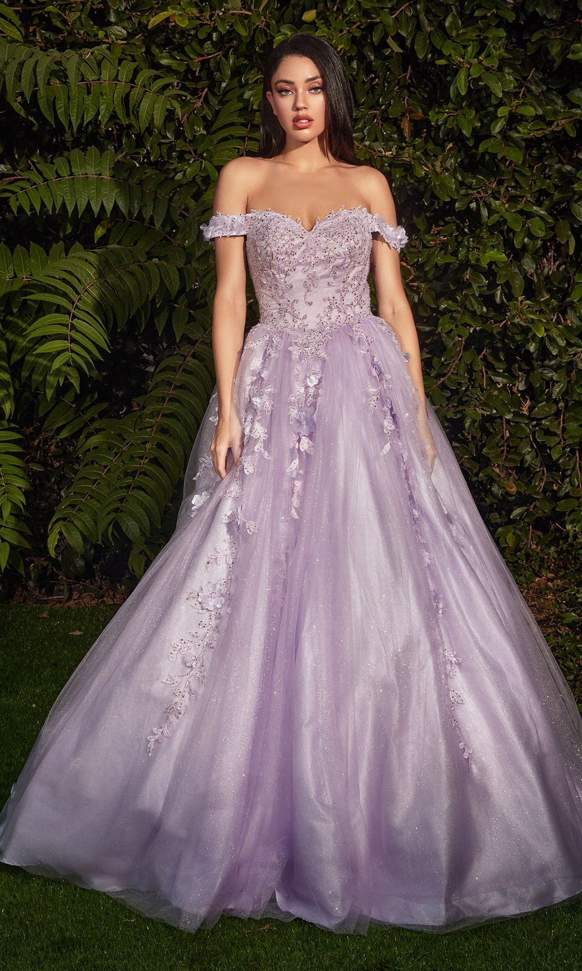 A woman stands outdoors amid greenery, wearing the Off-Shoulder Long Sweetheart Prom Ball Gown CD0185, featuring floral-lace appliques and a full tulle skirt in light purple with delicate floral embellishments.